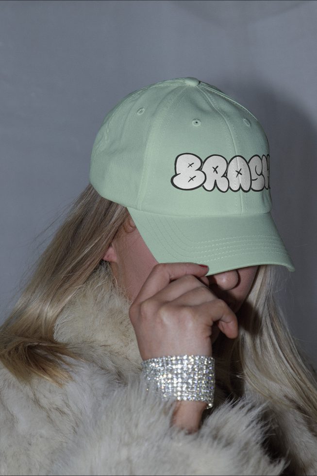 Stylish streetwear cap mockup featuring bold font, modern design, worn by a model with hidden face and sparkling wrist accessory.